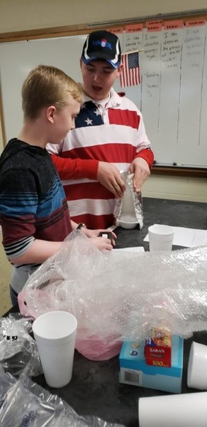 Students discover if a coat keeps a snowman from melting